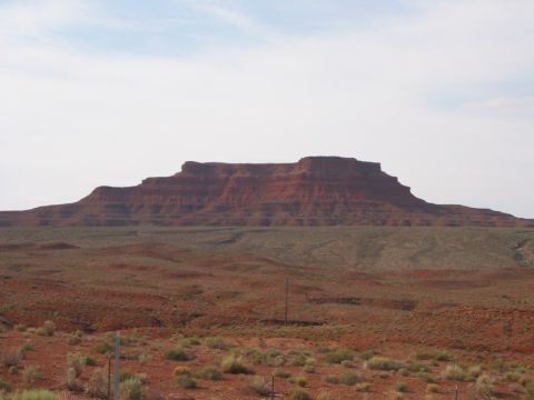 1997 Ford Ranger - A vast desert landscape features layered red rock mesas under a hazy sky, with sparse vegetation in the foreground.