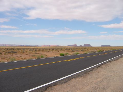 1997 Ford Ranger - A long, empty highway stretches through a desert landscape towards distant rock formations under a partly cloudy sky.