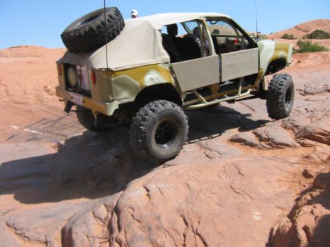 1997 Ford Ranger - Modified off-road vehicle navigates a rocky terrain under a clear blue sky.