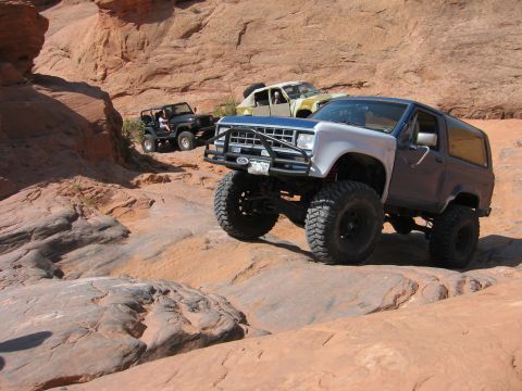 1997 Ford Ranger - Three off-road vehicles navigate a challenging rocky path in a desert canyon.
