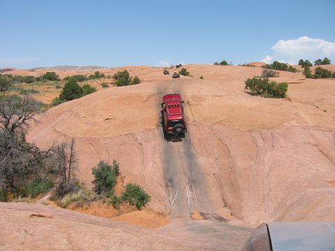 1997 Ford Ranger - Several off-road vehicles navigate a steep, rocky path under a clear blue sky.