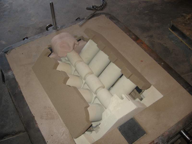 Open sand-casting mold with cylindrical cores set in place, ready to close for pouring