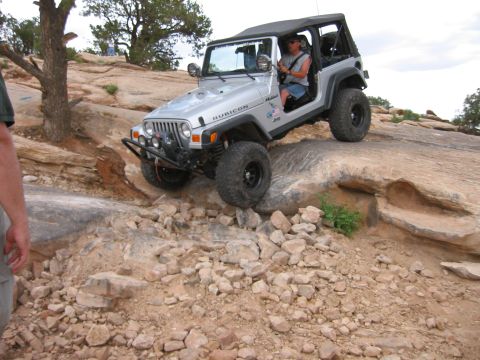 1997 Ford Ranger - A silver Jeep Wrangler Rubicon navigates a rocky trail, demonstrating its off-road capabilities.
