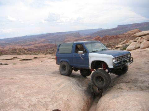 1997 Ford Ranger - This modified SUV is shown off-roading on a rocky desert landscape under a cloudy sky.