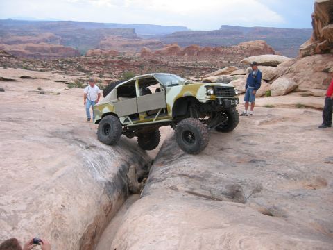 1997 Ford Ranger - A heavily modified truck is carefully driven over a narrow rock obstacle in a desert canyon.