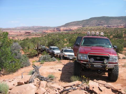 1997 Ford Ranger - A line of off-road vehicles navigates a rocky, arid terrain under a clear blue sky.