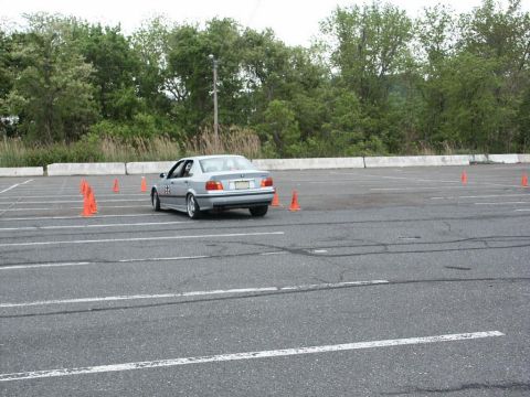 2001 Mercury Grand Marquis - Silver BMW E36 sedan maneuvers through an autocross course marked by orange cones.