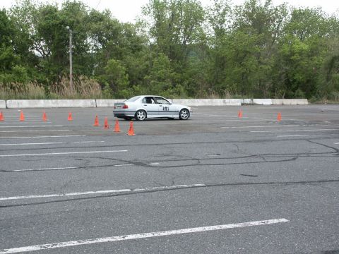 2001 Mercury Grand Marquis - A silver BMW E36 sedan is seen on a race track, maneuvering through a course defined by orange traffic cones.