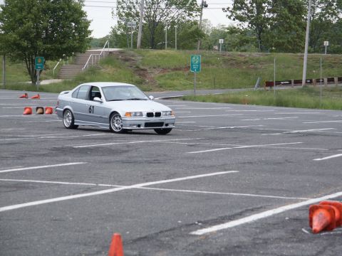 2001 Mercury Grand Marquis - A silver BMW sedan, identified by its racing number 61, navigates an autocross course on a paved lot.
