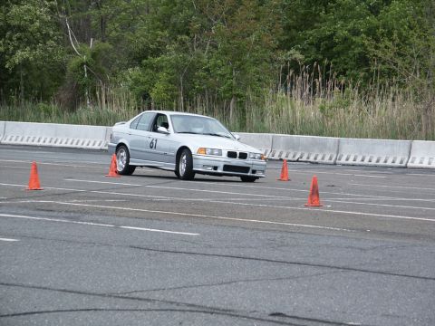 2001 Mercury Grand Marquis - A silver BMW E36 sedan participates in an autocross event, maneuvering around orange cones on a paved track.