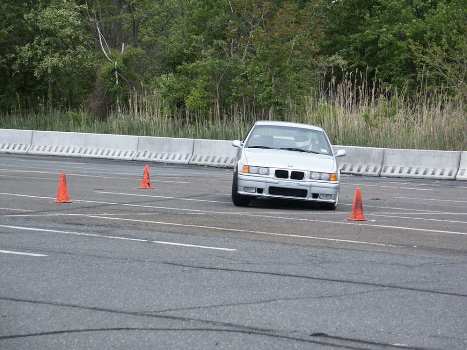 Silver BMW E36 sedan on a race track with orange cones