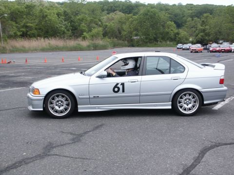 2001 Mercury Grand Marquis - Silver BMW E36 sedan with racing number 61 on the door participates in an autocross event.