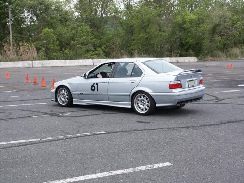 2001 Mercury Grand Marquis - A silver BMW sedan navigates an autocross course, indicated by the orange cones and racing number on its door.