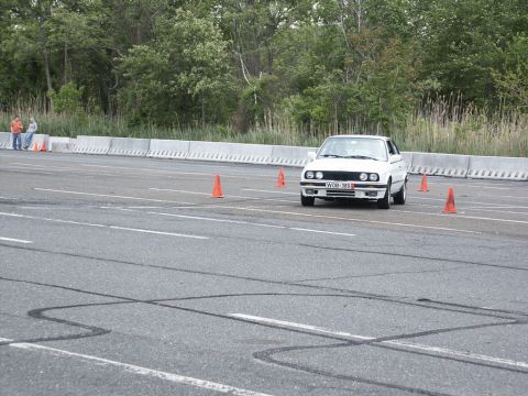 2001 Mercury Grand Marquis - A white BMW E30 navigates an autocross course, marked by orange cones on the asphalt track.