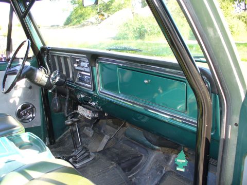 1978 Ford Bronco - The interior of a 1978 Ford Bronco features a green dashboard, roll cage, and aftermarket radio.