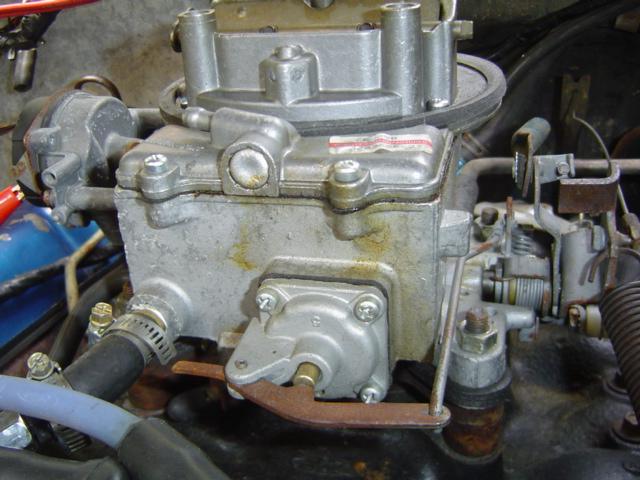 Aluminum two-barrel carburetor mounted on an engine intake with linkage and vacuum hoses