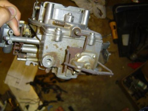 1979 Ford Bronco - A close-up view of a carburetor, a crucial part of a vehicle's fuel system, being held by a hand.