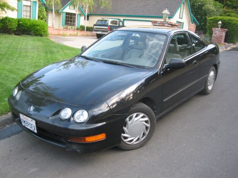 1995 Ford Bronco - Black Acura Integra coupe parked on a residential street in front of a house.