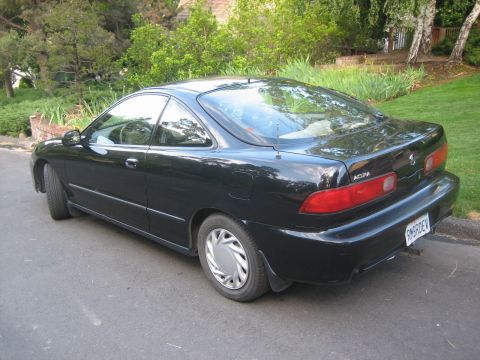 1995 Ford Bronco - A black coupe is parked on a street with trees and grass in the background. The rear of the vehicle is visible.