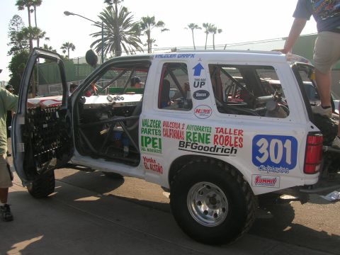 1992 Ford Explorer - White off-road SUV with racing decals and roll cage, driver's door open, parked on pavement.