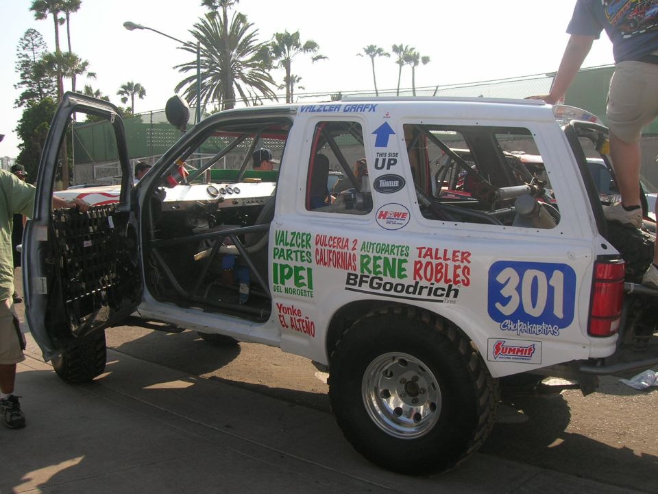 White off-road SUV with racing decals and roll cage, driver's door open