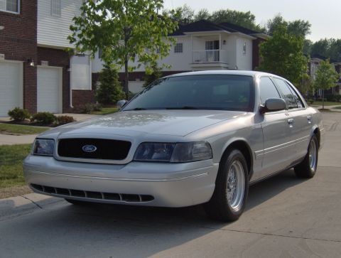 2002 Ford Crown Victoria - A silver 2002 Ford Crown Victoria sedan is parked in front of a residential building.
