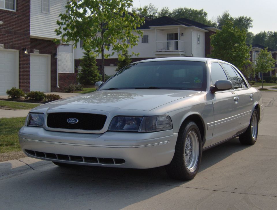 Silver 2002 Ford Crown Victoria sedan, front 3/4 view, parked on a suburban street