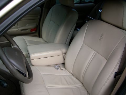 2000 Ford Crown Victoria - Front interior viewed through the open driver's door, showing tan leather bucket-style front seats with a fold-down center armrest console.…