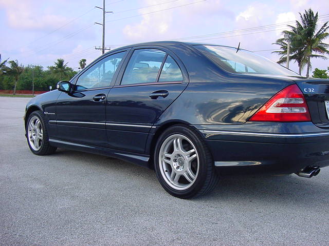 Dark blue sedan parked on asphalt, rear quarter view. 'C 32' badge visible on the trunk lid