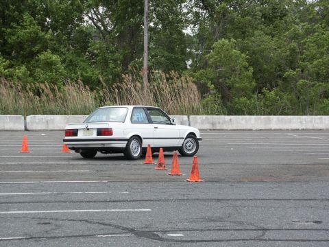 2001 Mercury Grand Marquis - A white BMW E30 coupe is seen from the rear during an autocross event on a paved lot.