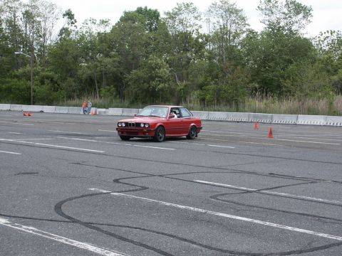 2001 Mercury Grand Marquis - A red BMW E30 coupe navigates an autocross course, leaving tire marks on the asphalt.