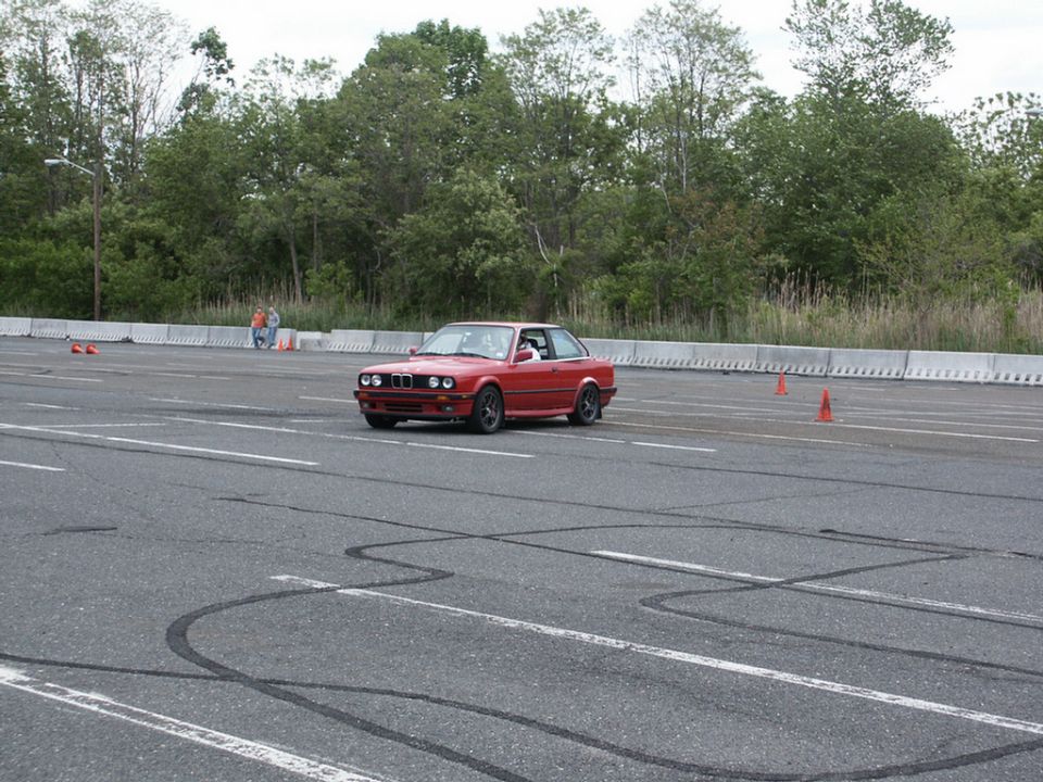 Red BMW E30 coupe on a race track with tire marks