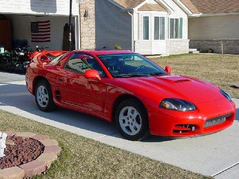 1994 Dodge Stealth - A red sports car is parked in a driveway in front of a house, with an American flag hanging in the open garage.