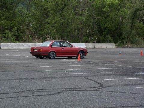 2001 Mercury Grand Marquis - Red BMW E30 coupe navigates an autocross course on a cloudy day.