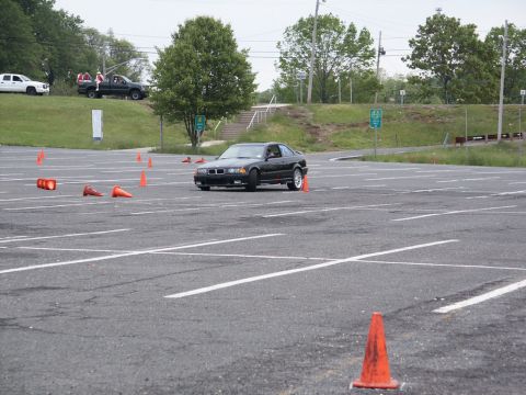 2001 Mercury Grand Marquis - A black BMW coupe navigates an autocross course on a paved lot with orange cones.