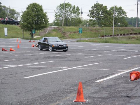 2001 Mercury Grand Marquis - A black BMW E36 coupe navigates a course marked by orange cones on a sunny day.