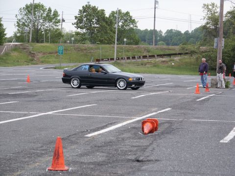 2001 Mercury Grand Marquis - A black BMW E36 coupe navigates a course marked by orange cones in a parking lot.
