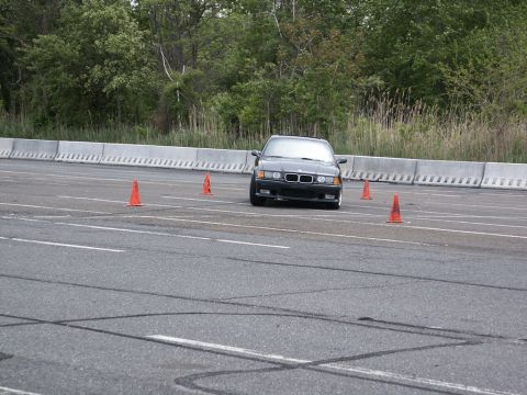 2001 Mercury Grand Marquis - A black BMW E36 coupe is seen from the front on an asphalt course marked with orange cones.