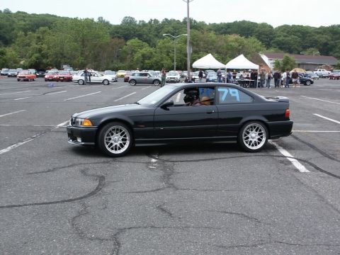 2001 Mercury Grand Marquis - A black BMW E36 coupe is seen at an event, with other vehicles and tents in the background.