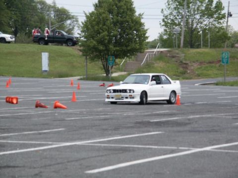 2001 Mercury Grand Marquis - A white BMW E30 M3 is seen maneuvering through an autocross course marked by orange cones.