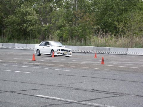 2001 Mercury Grand Marquis - A white BMW E30 M3 is shown on a race track, maneuvering around orange cones.
