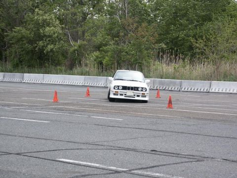 2001 Mercury Grand Marquis - A white BMW E30 navigates a course marked by orange cones on an asphalt track.