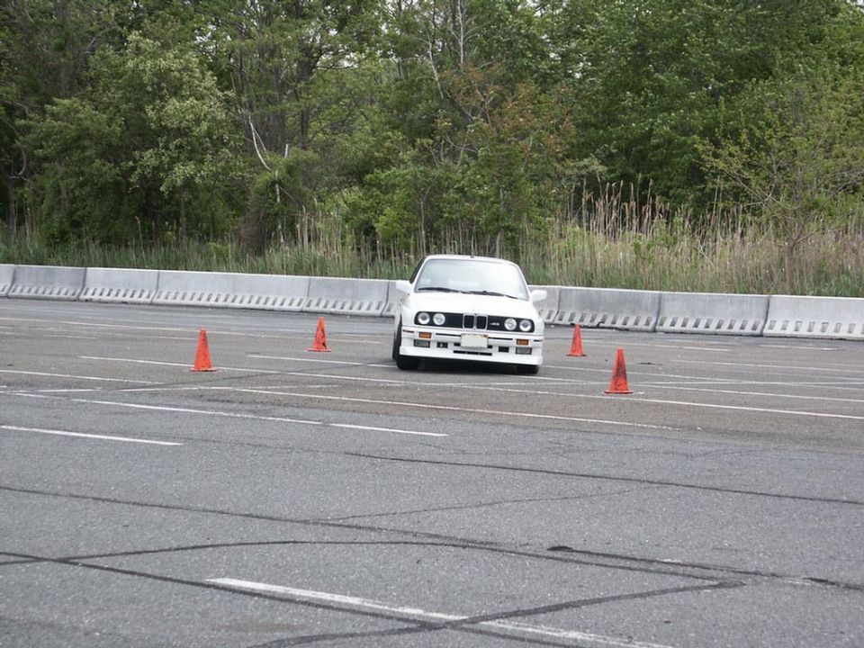 White BMW E30 driving on a track with orange cones