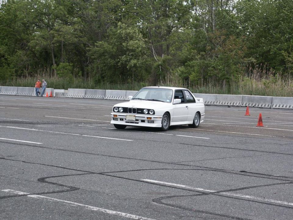 White BMW E30 M3 with racing numbers on door, on a track