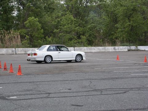 2001 Mercury Grand Marquis - A white BMW E30 M3 navigates a course marked by orange cones on a paved track.
