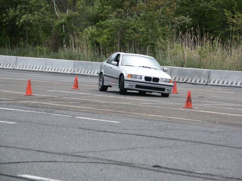 2001 Mercury Grand Marquis - Silver BMW E36 sedan navigates an autocross course marked by orange cones.
