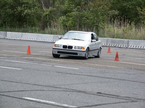 2001 Mercury Grand Marquis - A silver BMW E36 sedan is seen on a race track, maneuvering around orange cones during an autocross event.