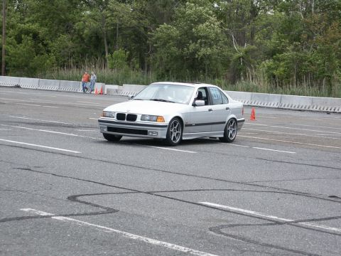 2001 Mercury Grand Marquis - A silver BMW E36 sedan navigates an autocross course on a cloudy day.