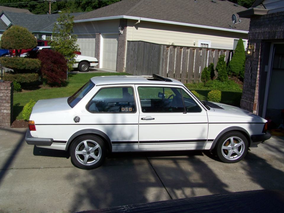 White 1984 Volkswagen Jetta parked in a driveway, side view. The car has a sunroof and black trim