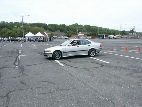 2001 Mercury Grand Marquis - A silver sedan with racing numbers navigates an autocross course, with tents and other vehicles visible in the background.